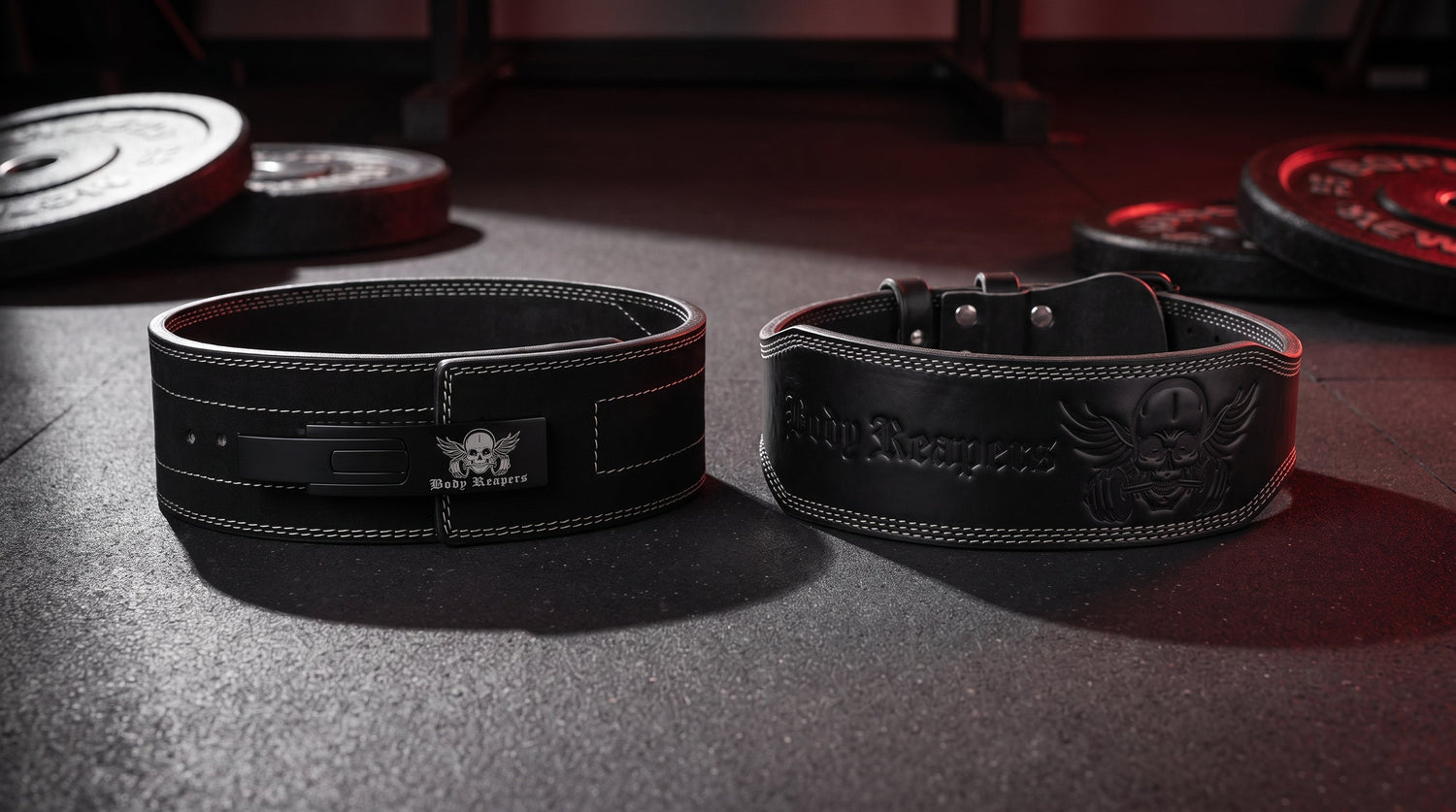 Body Reapers 10mm lever belt and 7mm double-prong belt side by side on a dark gym floor