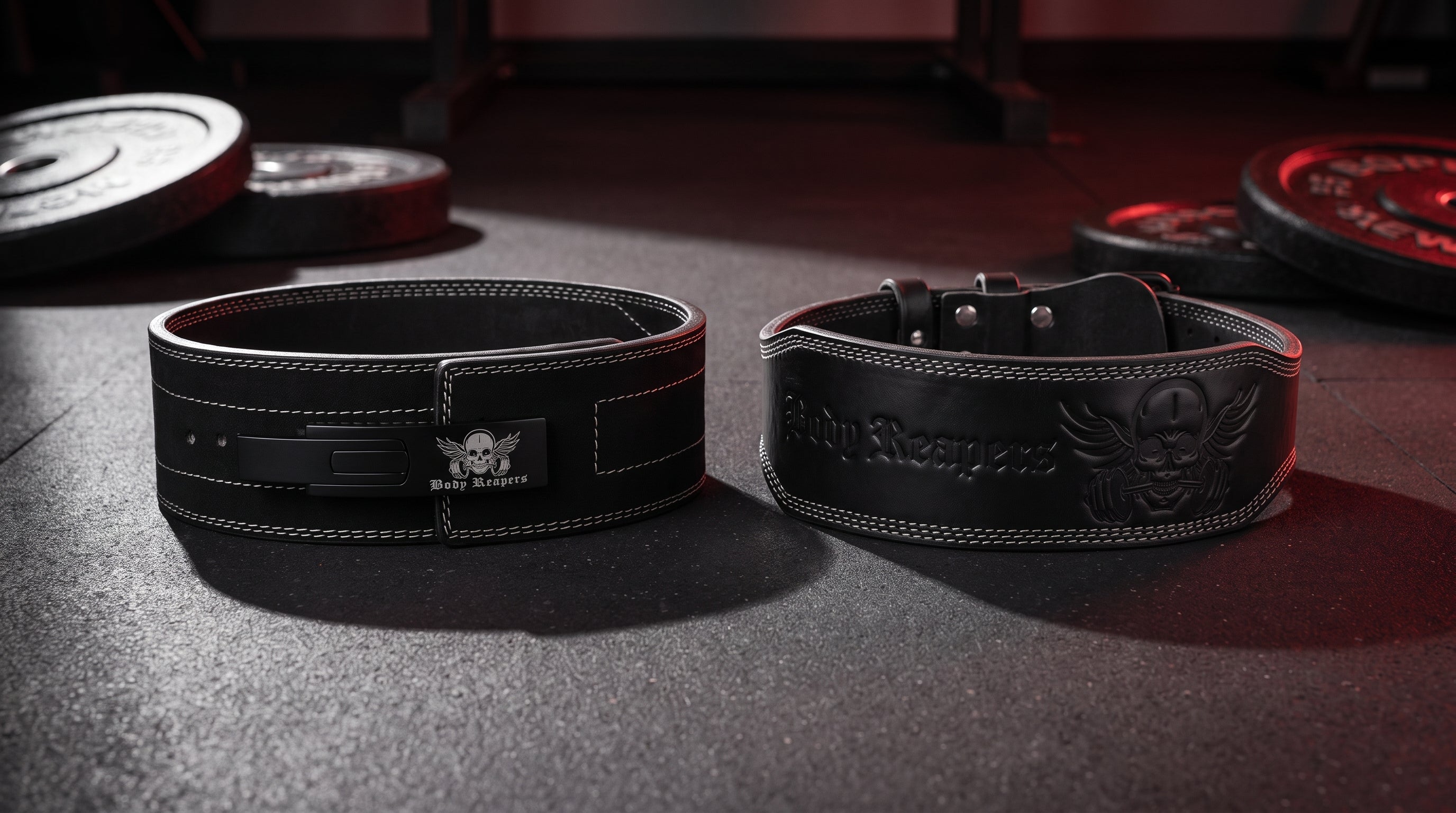 Body Reapers 10mm lever belt and 7mm double-prong belt side by side on a dark gym floor