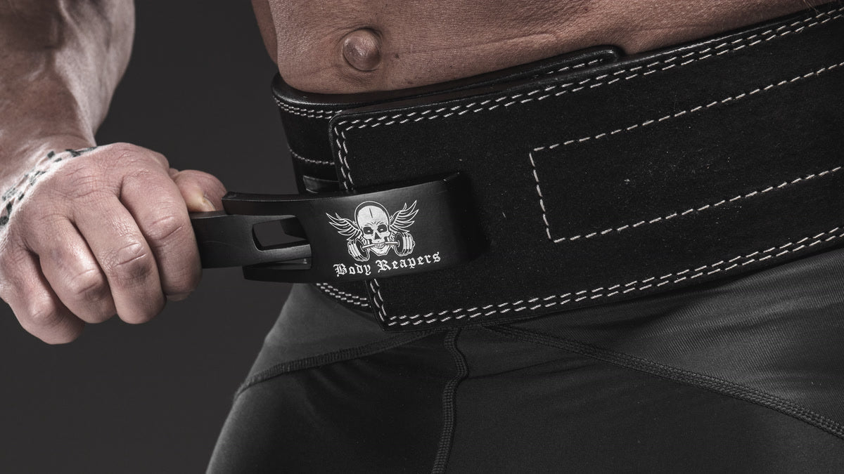 Close-up of an athlete's hand fastening the lever buckle on a black Body Reapers lever belt