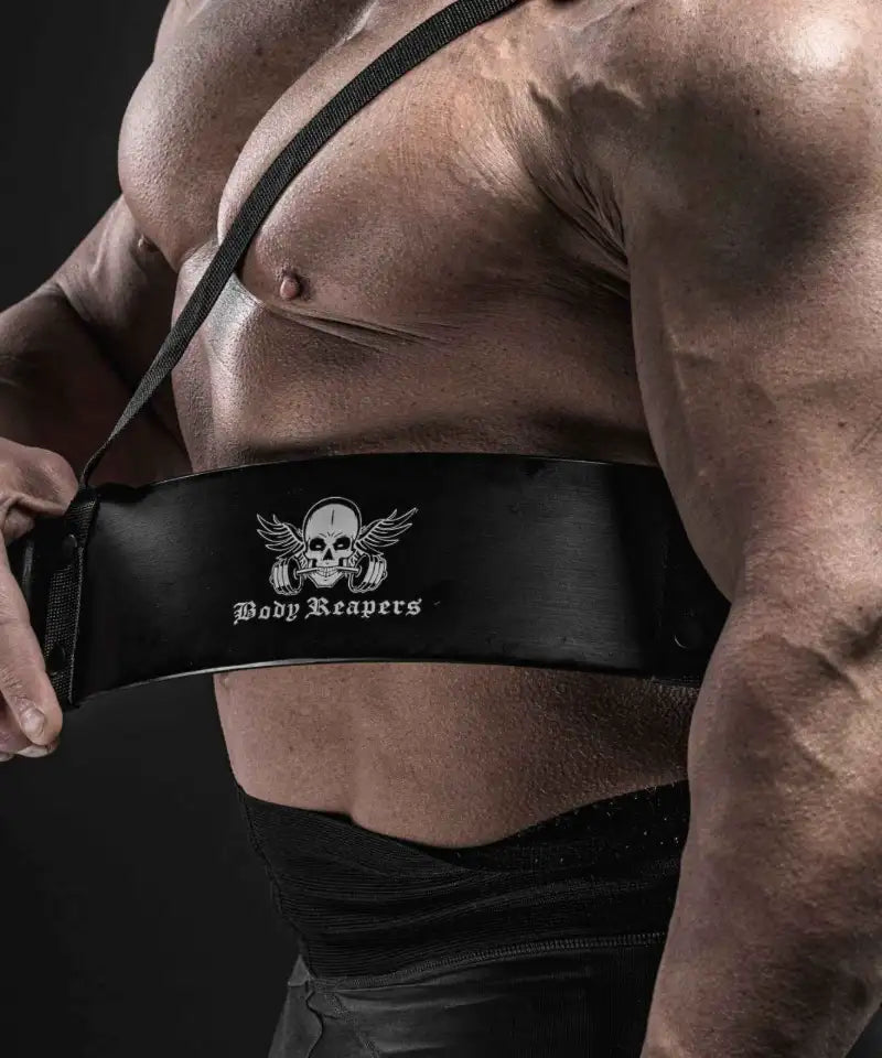 Body Reapers athlete holding a black leather weightlifting belt with the winged skull logo